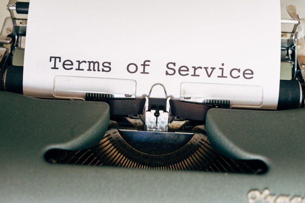 A typewriter holds a piece of paper with "Terms of Service" written on it.