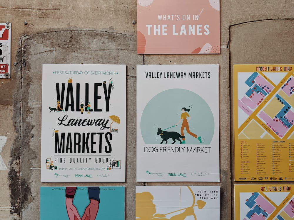 Seven flyers in a grid on a concrete wall, with illustrations, varied font, and bright blues, yellows, and pinks, demonstrate a range of graphic design.